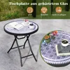 A round folding table with a mosaic top, set outdoors on a patio. The table has a book, a small cake, and a bowl of blueberries on it. A close-up inset shows flowers and a cup of coffee on a similar table. Podgląd zdjęcia produktu