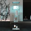 A glass display cabinet with items on its shelves, set against a marble-patterned wall and a dark background. Náhled obrázku produktu