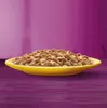 A yellow bowl filled with cat food sits on a purple wooden surface, with a blurred purple background. Produktbild-Vorschau