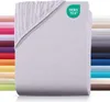 A stack of folded fitted sheets, with a close-up view of the top sheet showing the elasticized corner. A green OEKO-TEX logo is visible on the top right corner of the main sheet. To the left and right of the main product are stacks of sheets in various col Produktbild-Vorschau