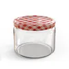 A clear studio shot of an empty glass jar with a red and white checkered lid. Náhled obrázku produktu