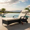 A black rattan sun lounger with beige cushions is placed on a wooden deck next to a swimming pool, with a scenic view of the ocean and islands in the background. Anteprima dell’immagine prodotto