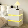 A white nightstand with yellow LED lighting next to a bed. Náhľad obrázku produktu