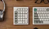 A top-down view of a mechanical keyboard and a numpad on a wooden desk. Produktbild-Vorschau