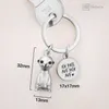 A close-up of a silver keychain with a meerkat charm and a round pendant with German text. Produktbild-Vorschau
