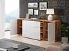 A modern sideboard with white drawers and wooden accents, set in a living room with framed pictures on a brick wall. Náhled obrázku produktu