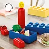 A collection of LEGO-themed lunch containers and a water bottle arranged on a wooden surface, with a sandwich in the foreground. Anteprima dell’immagine prodotto