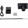 A flat lay of camera accessories including a camera, charger, battery, and wrist strap. Podgląd zdjęcia produktu