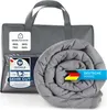 A gray weighted blanket is rolled up and placed next to its gray storage bag. There are several labels and text overlays on the image. Produktbild-Vorschau