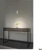 A modern console table with a marble-like top and black metal legs, illuminated by a pendant light. A small vase with greenery sits on the table. Produktbild-Vorschau