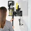 A woman is holding a cordless vacuum cleaner that is mounted on a charging station on the wall. Produktbild-Vorschau