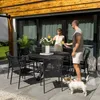 A couple and their dog enjoying drinks on a patio next to a dining set. Produktbild-Vorschau