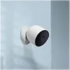 A white security camera is mounted on a light blue wall. Voir les images du produit