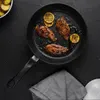A frying pan with cooked chicken and lemon slices on a black surface. Produktbild-Vorschau