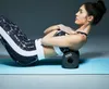 A woman is using a foam roller for self-massage on a yoga mat. Produktbild-Vorschau