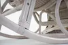 A close-up view of the base and legs of a white rocking chair made of rattan. Produktbild-Vorschau