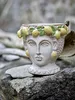 A ceramic pot shaped like a woman's head, decorated with lemons and leaves, sits on rocks. Náhľad obrázku produktu