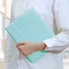 A person in a white shirt holds a mint green tablet case. Produktbild-Vorschau