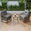 A rattan furniture set with two rocking chairs and a small table on a wooden deck, surrounded by lush greenery and a light-colored wall. Produktbild-Vorschau