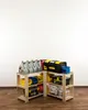 Two wooden shelving units are arranged in an L-shape, filled with various storage containers, toolboxes, and bottles of liquid. The shelves are made of light-colored wood, and the background is a plain white wall with a wooden floor. Produktbild-Vorschau