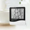 A digital thermometer and hygrometer is placed on a table next to a white mug. Anteprima dell’immagine prodotto
