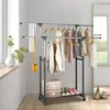 A double rail clothes rack with clothes hanging on it, placed in a room with a window and a mirror. Náhľad obrázku produktu