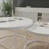 A modern living room setting with two white nesting coffee tables, one with an open book and a small decorative item, and the other with two lit candles in glass holders. A white sideboard with fluted doors is visible in the background. Voir les images du produit