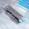 Two rolled-up vacuum seal bags containing dark gray clothing are shown on a light gray surface. Podgląd zdjęcia produktu
