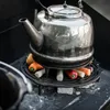 A metal kettle is placed on a cast iron grate with vegetables underneath, suggesting it is being heated over a fire. Produktbild-Vorschau