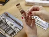 A person's hands assembling a wooden model kit of a building. Produktbild-Vorschau