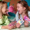 Two young girls are playing cards on a bed. Produktbild-Vorschau