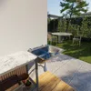 An outdoor sink area next to a wall, with a table and chairs in the background. Produktbild-Vorschau