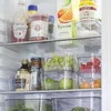 A close-up view of a refrigerator shelf filled with various food items and storage containers. Produktbild-Vorschau