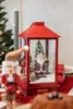 A festive Christmas scene with a nutcracker figure and a red lantern containing a Santa Claus figurine and miniature Christmas trees. Produktbild-Vorschau