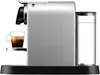 Side view of a silver Nespresso coffee machine with a glass cup of espresso on the drip tray and a transparent water reservoir on the right. Podgląd zdjęcia produktu