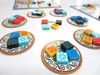 A tabletop board game with colorful tiles arranged on small plates and a game board in the background. Anteprima dell’immagine prodotto