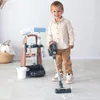 A young boy is playing with a toy cleaning set, including a vacuum cleaner and a cleaning cart. Produktbild-Vorschau