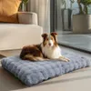 A dog is lying on a gray dog bed in a well-lit room with a sofa and large windows. Anteprima dell’immagine prodotto