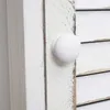 A close-up of a white wooden knob on a white wooden surface, with slatted wood in the background. Náhľad obrázku produktu