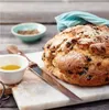 A loaf of bread with some accompaniments on a cutting board. Anteprima dell’immagine prodotto