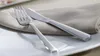 A fork and knife are placed on a white plate with a folded napkin. Produktbild-Vorschau