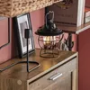 A vintage-style black lantern sits on a wooden cabinet next to a framed picture. Náhled obrázku produktu