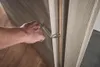 A person's hand is using a tool to install or adjust a door. Produktbild-Vorschau