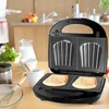 A sandwich maker on a wooden table with kitchenware in the background. Produktbild-Vorschau