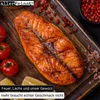 A grilled salmon fillet on a wooden board, surrounded by tomatoes, lemon slices, and peppercorns. Náhled obrázku produktu