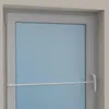 A close-up view of a white window frame with a light blue glass pane and a white adjustable tension rod installed horizontally across the lower part of the window. Produktbild-Vorschau