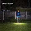 A young boy walks across a grassy lawn at night, holding a flashlight that illuminates the ground in front of him. Produktbild-Vorschau