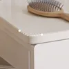 Close-up of a light beige furniture surface with a hairbrush on it. The surface has rounded edges. Podgląd zdjęcia produktu