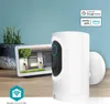 A smart camera is shown on a wooden surface with a tablet displaying a house view and a plant in the background. Produktbild-Vorschau
