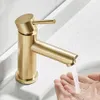 A close-up shot of a gold-colored faucet with water running into a person's hands. Produktbild-Vorschau